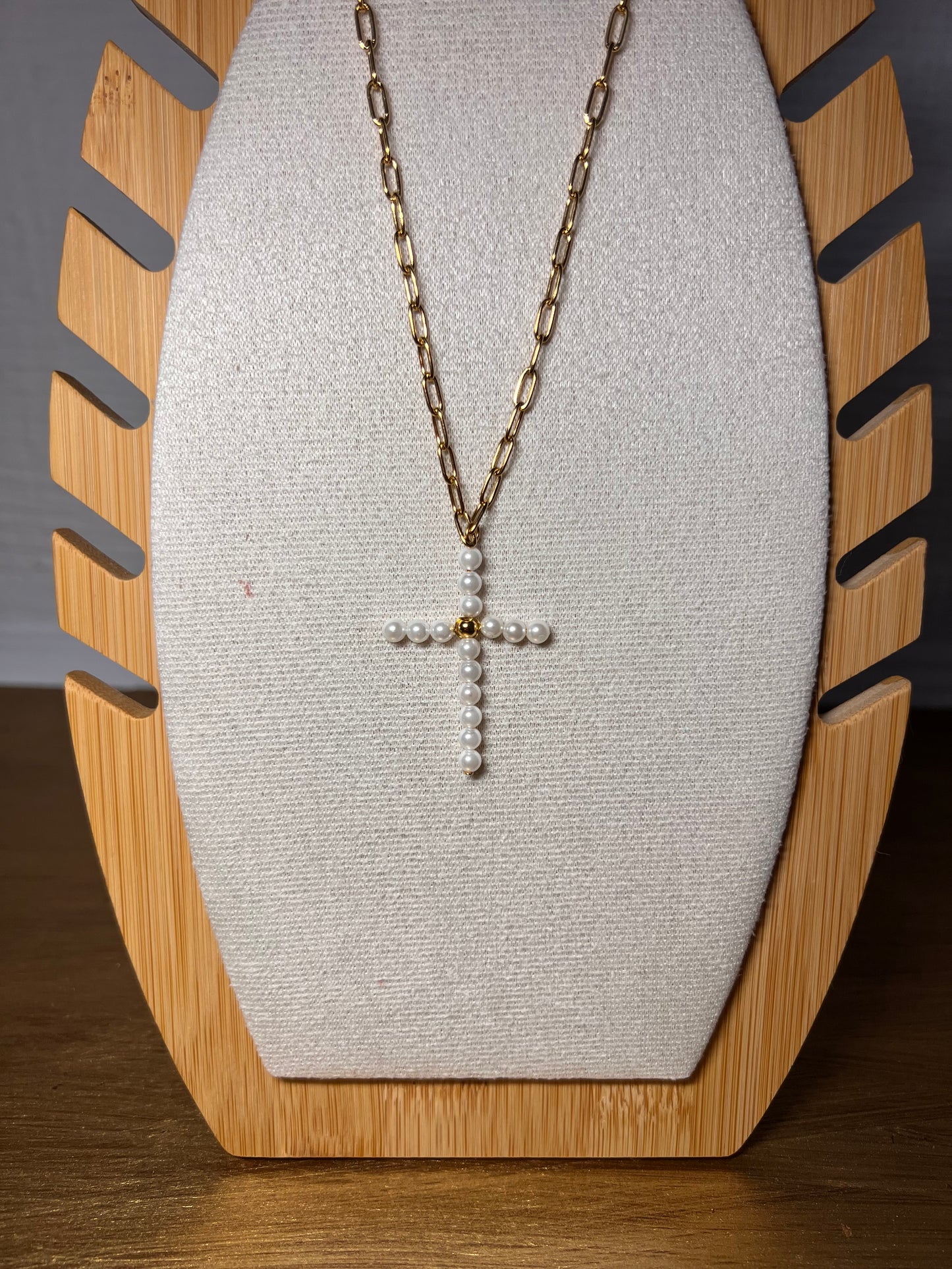 Collar cadena dorada con cruz de perlas sobre fondo blanco