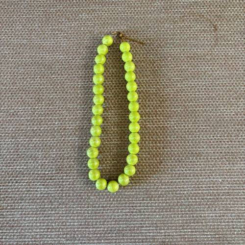 Collar de bolas medianas color verde nácar sobre fondo beige