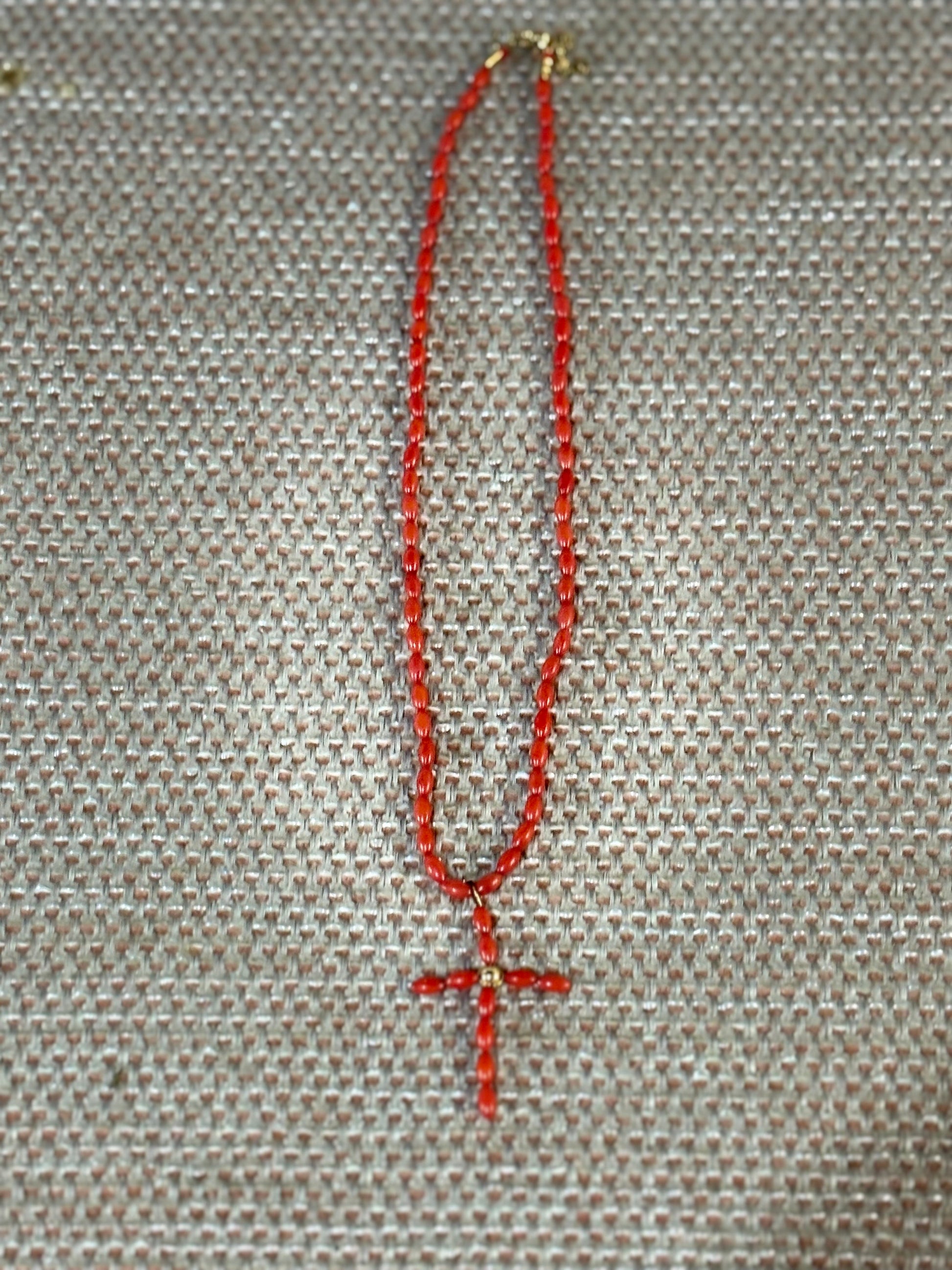 “Collar de coral rojo natural con cuentas ovaladas sobre fondo beige”