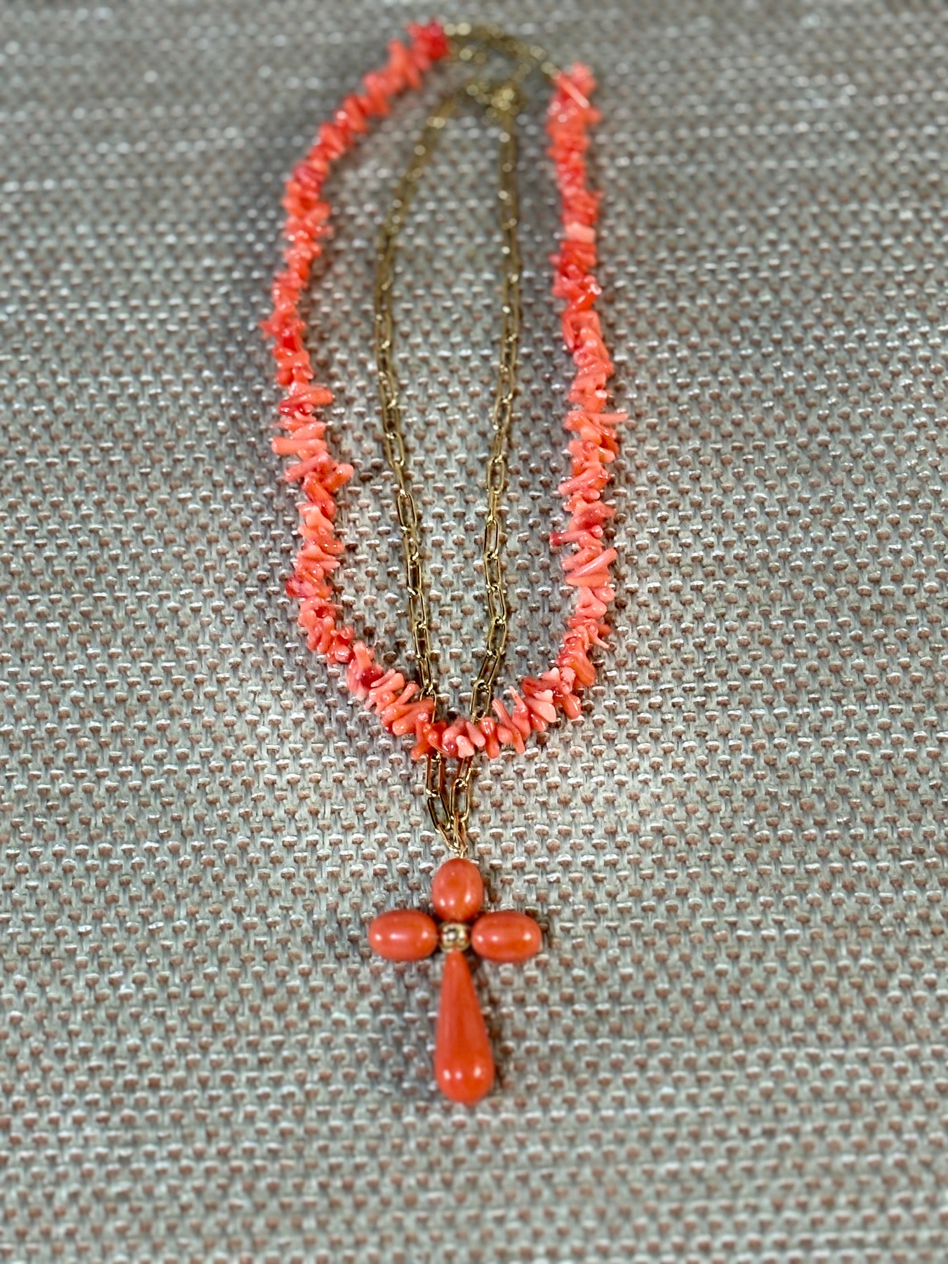 “Gargantilla de coral rosa natural con cuentas irregulares y cruz coral sobre fondo beige”