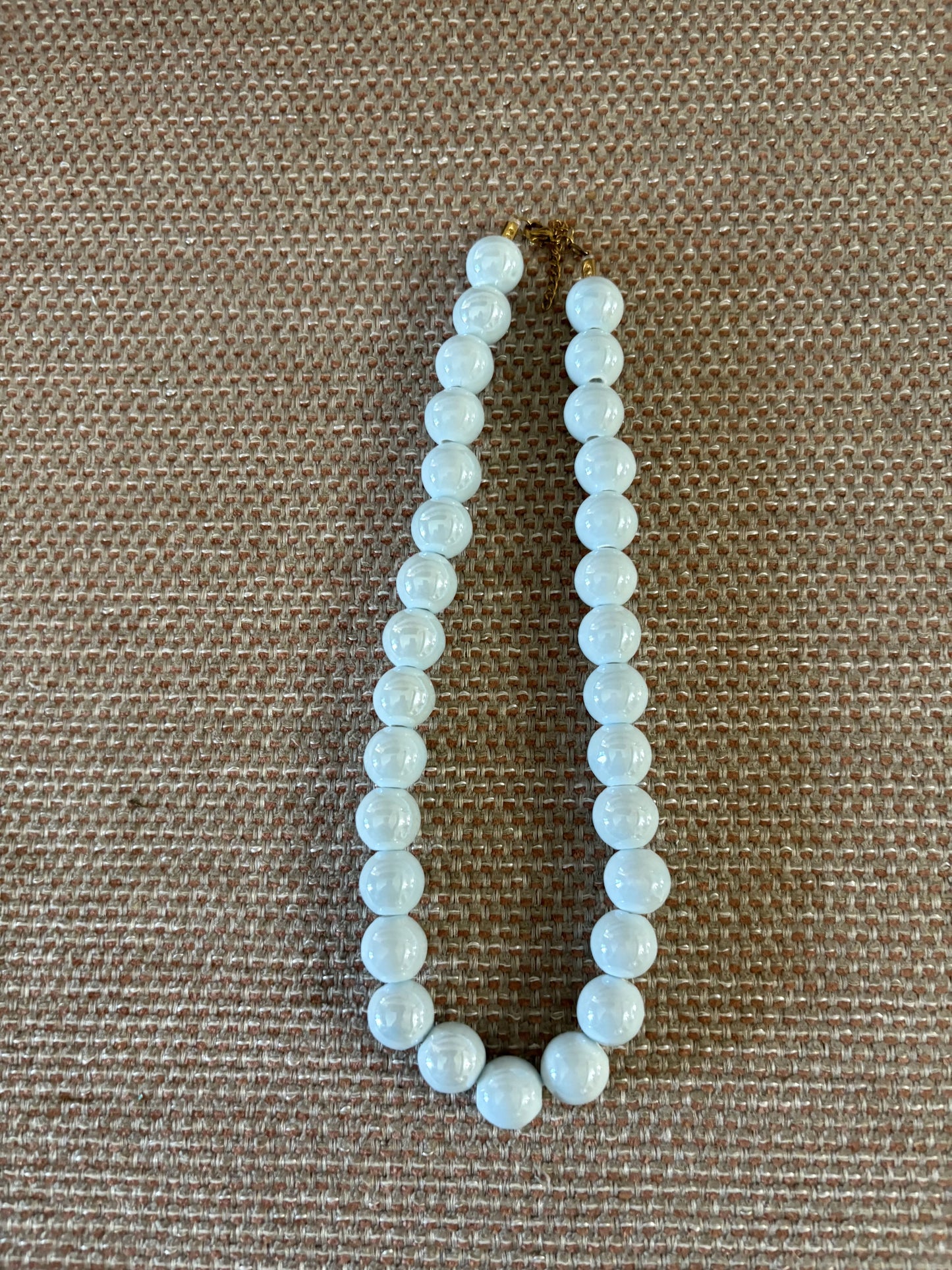 “Collar de resina celeste con bolas sobre fondo blanco”