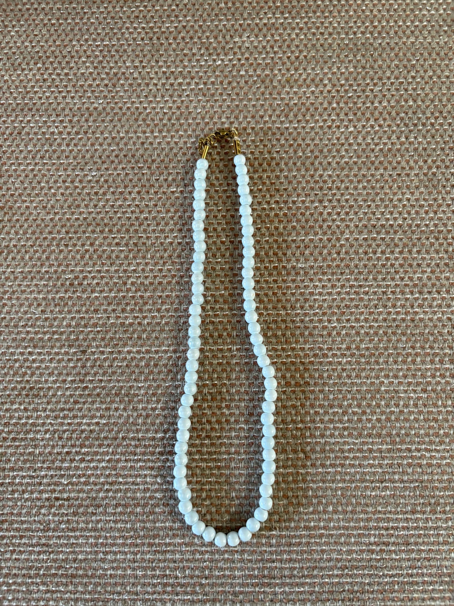 “Collar de bolas celestes pequeñas sobre fondo beige”