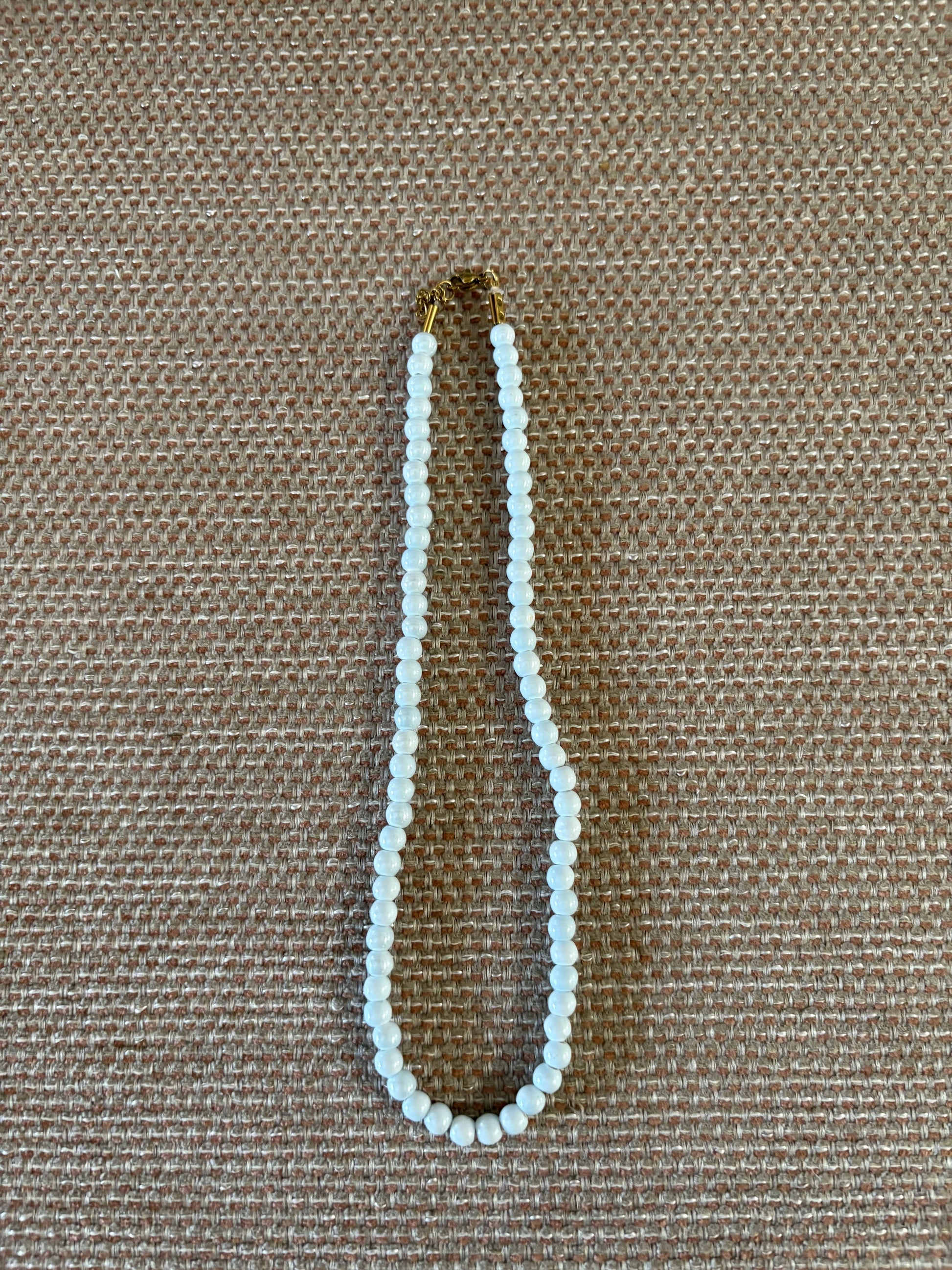 “Collar de bolas celestes pequeñas sobre fondo beige”