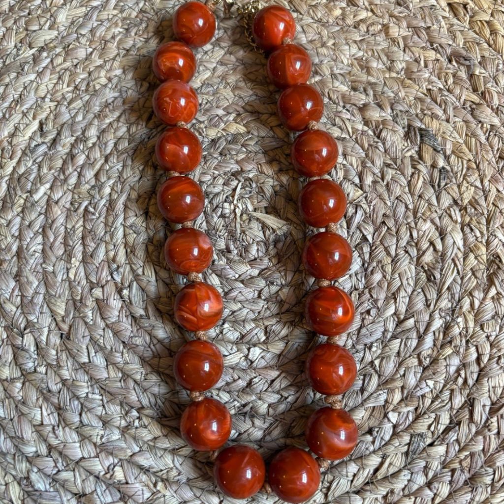 Collar de bolas marmoleadas en tono coral.