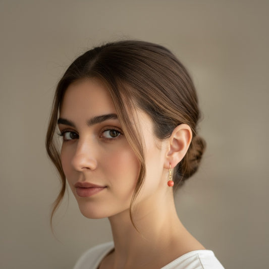 Pendiente de acero con cuenta pequeña de coral sobre fondo blanco